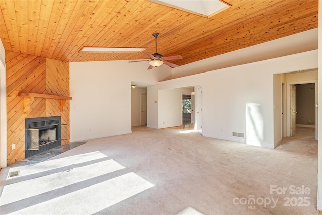 unfurnished living room with a skylight, a fireplace, wood ceiling, visible vents, and carpet