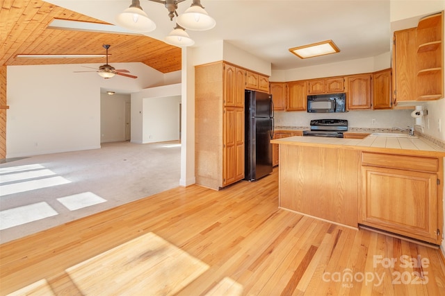 kitchen featuring open shelves, a peninsula, a sink, light wood-style floors, and black appliances