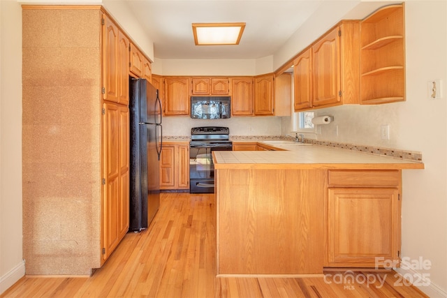 kitchen with open shelves, a sink, light wood-type flooring, a peninsula, and black appliances