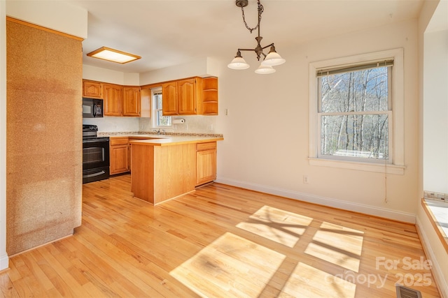 kitchen featuring light wood-type flooring, visible vents, a peninsula, and black appliances