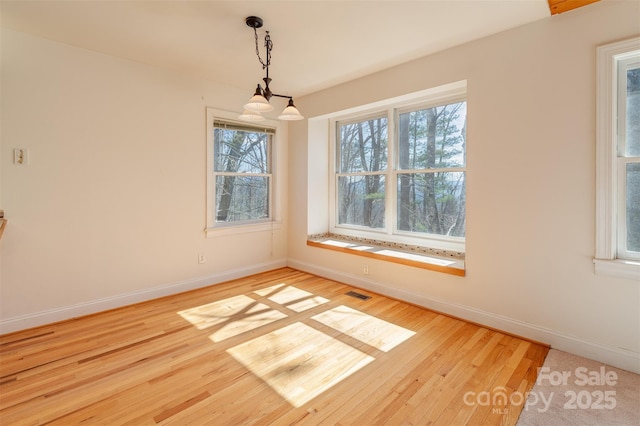 spare room featuring visible vents, baseboards, and wood finished floors