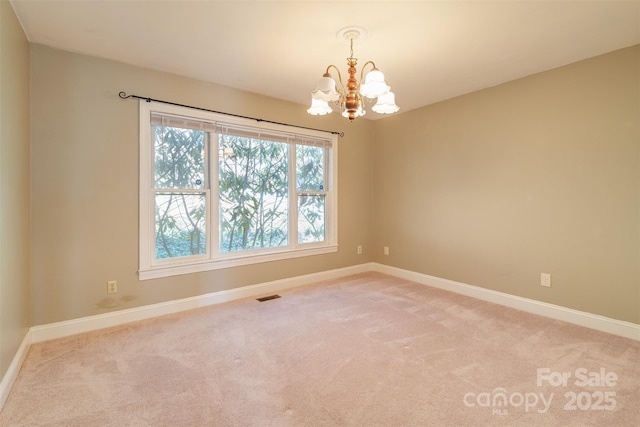 spare room with a chandelier, carpet, visible vents, and baseboards