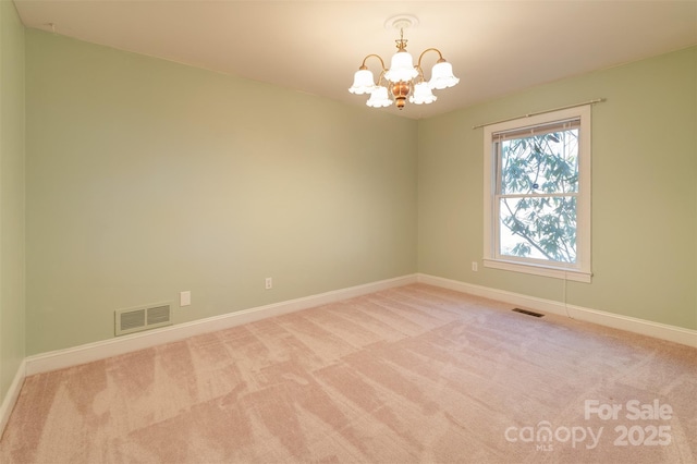 spare room featuring carpet floors, an inviting chandelier, baseboards, and visible vents