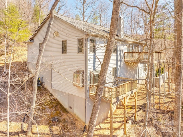 view of home's exterior featuring a chimney, stairway, and a deck