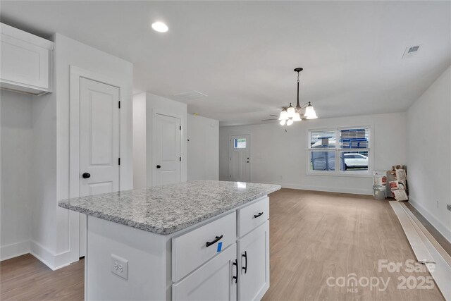 425 Messner St, Salisbury, NC 28144 - kitchen with light wood finished floors, baseboards, white cabinets, a kitchen island, and light stone countertops