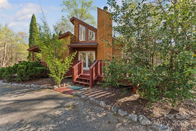 back of house with a chimney, a deck, and french doors