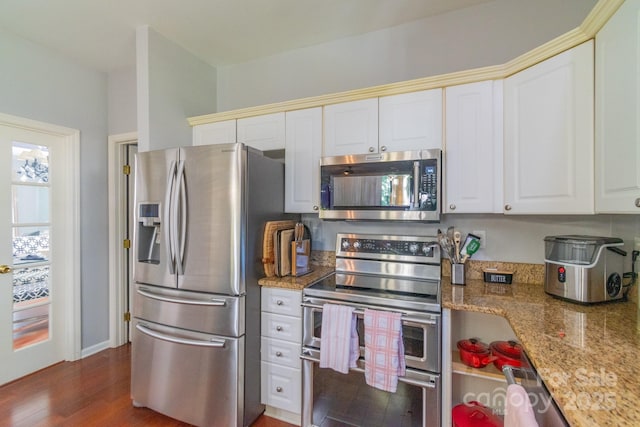 kitchen with appliances with stainless steel finishes, white cabinets, light stone counters, and wood finished floors