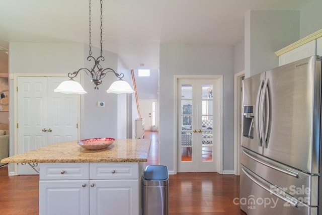 kitchen featuring light stone counters, dark wood-style flooring, decorative light fixtures, stainless steel refrigerator with ice dispenser, and white cabinetry