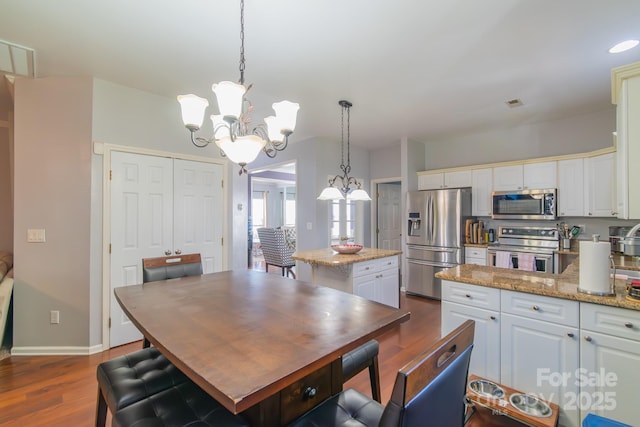 dining area featuring baseboards, dark wood-type flooring, visible vents, and an inviting chandelier