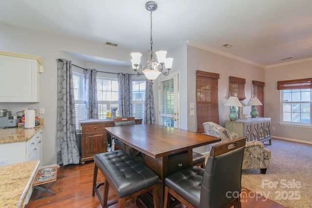 dining room with dark wood-style flooring, crown molding, a notable chandelier, visible vents, and baseboards