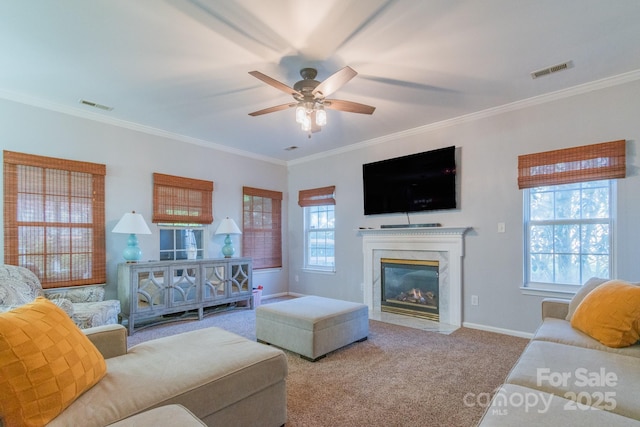 carpeted living room featuring visible vents, crown molding, a fireplace, and ceiling fan