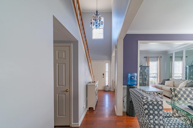 hall with a notable chandelier, crown molding, baseboards, and wood finished floors