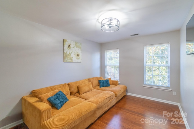 living area with wood finished floors, visible vents, and baseboards