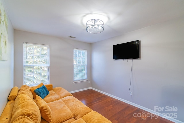 unfurnished living room with baseboards, visible vents, and dark wood-type flooring