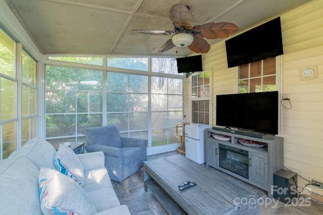 living area featuring wood walls and a ceiling fan