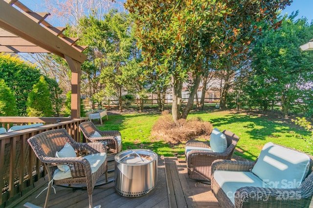 wooden terrace with a fire pit, a yard, and fence