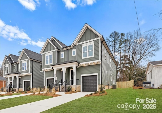 view of front of house featuring an attached garage, board and batten siding, fence, driveway, and a front lawn