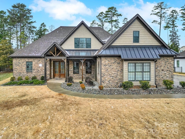 view of front of house featuring french doors, a standing seam roof, a front lawn, and brick siding