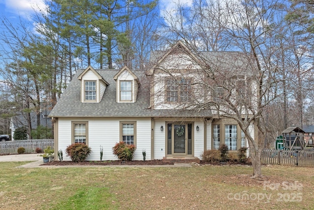 view of front of house with a front lawn, a shingled roof, and fence