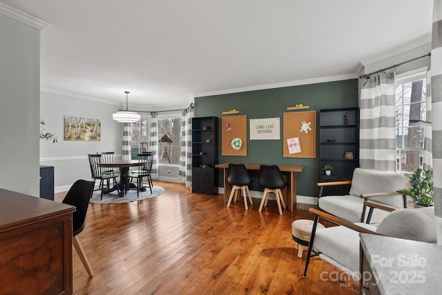 living area featuring baseboards, hardwood / wood-style floors, and crown molding