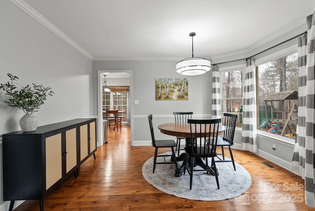 dining space featuring baseboards, crown molding, visible vents, and hardwood / wood-style floors