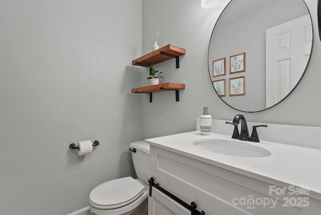 half bathroom featuring toilet, baseboards, and vanity