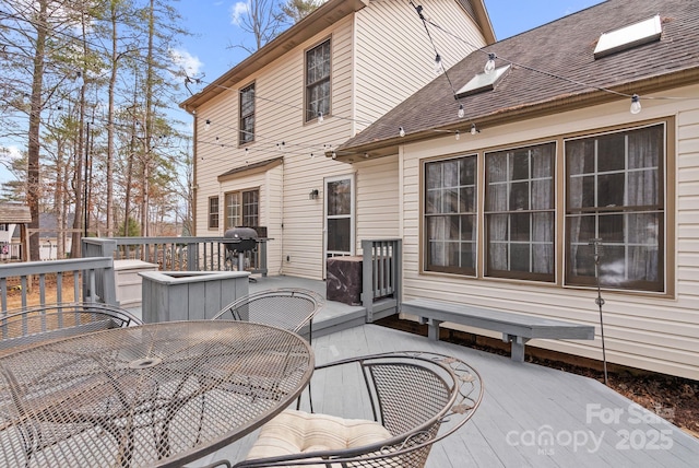 wooden terrace featuring outdoor dining space and grilling area