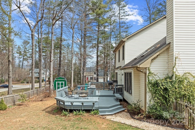 view of yard with an outbuilding, fence, a wooden deck, and a storage shed