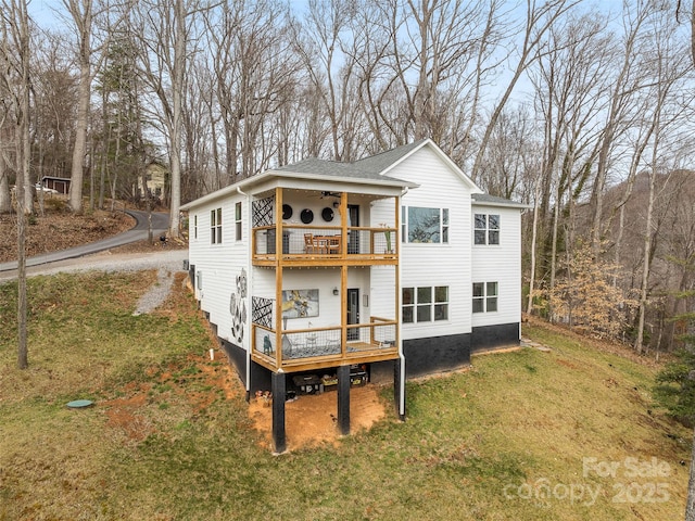 rear view of property featuring a lawn, a balcony, ceiling fan, roof with shingles, and a deck