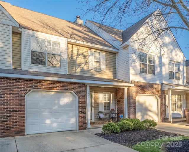 view of front of house featuring driveway, a garage, a chimney, and brick siding