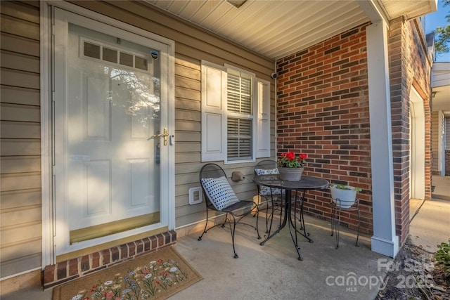 property entrance featuring a porch and brick siding