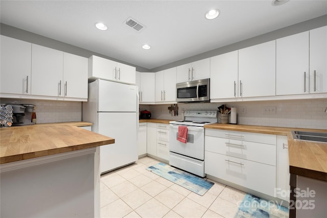 kitchen featuring white appliances, light tile patterned floors, visible vents, white cabinets, and wood counters