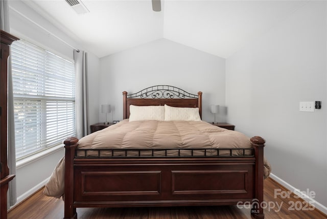 bedroom featuring baseboards, visible vents, vaulted ceiling, and wood finished floors