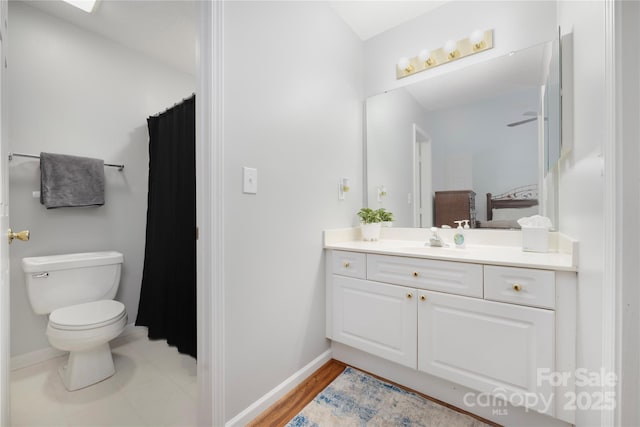 full bathroom with baseboards, vanity, and toilet