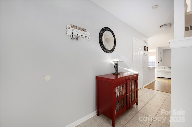 corridor featuring light tile patterned floors and baseboards