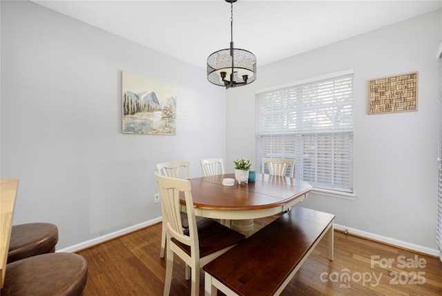 dining area featuring a notable chandelier, baseboards, and wood finished floors