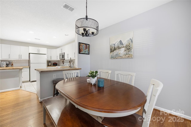 dining area with recessed lighting, visible vents, baseboards, light wood-style floors, and an inviting chandelier