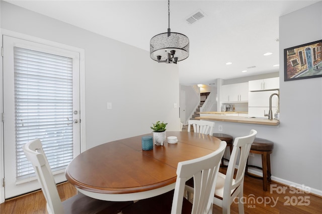 dining area featuring recessed lighting, wood finished floors, visible vents, stairway, and an inviting chandelier