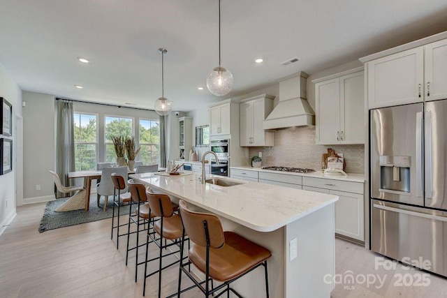 kitchen with tasteful backsplash, visible vents, a breakfast bar, custom exhaust hood, and appliances with stainless steel finishes