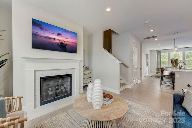 living room with visible vents, baseboards, stairway, recessed lighting, and light wood-style flooring