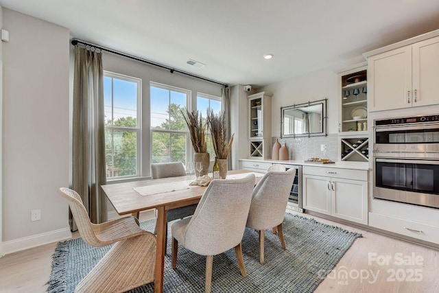 dining space with baseboards, recessed lighting, visible vents, wine cooler, and light wood finished floors