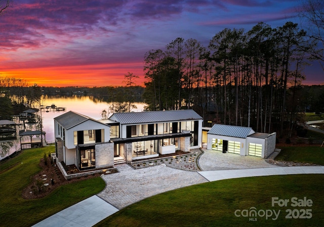 view of front of house with a lawn, metal roof, a water view, a standing seam roof, and a porch