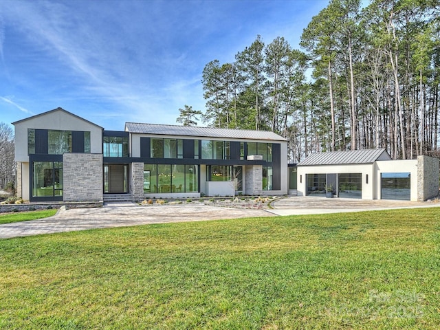 contemporary home with stone siding, a standing seam roof, metal roof, and a front lawn