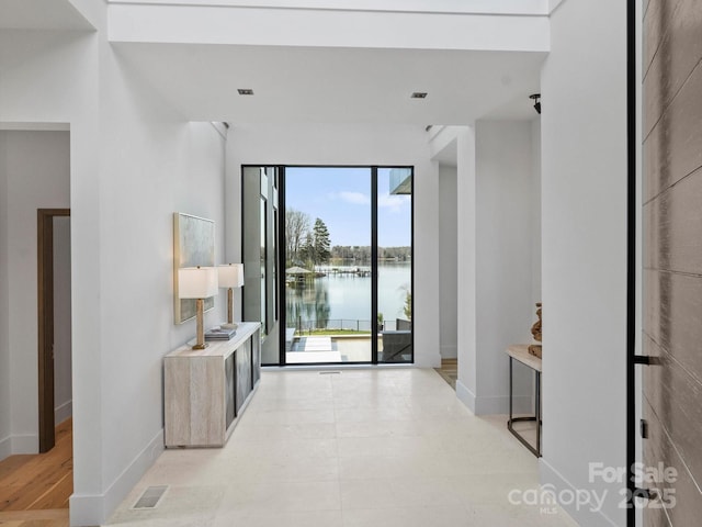 interior space with a water view, visible vents, and baseboards