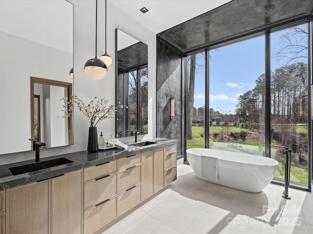 bathroom featuring double vanity, a freestanding tub, tile patterned flooring, and a sink