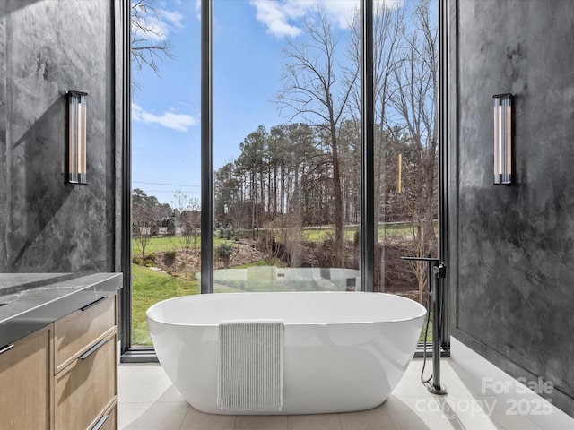 bathroom with a wall of windows, a soaking tub, vanity, and tile patterned floors