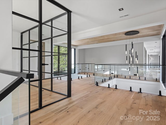 spare room with light wood-style floors, visible vents, and a wall of windows