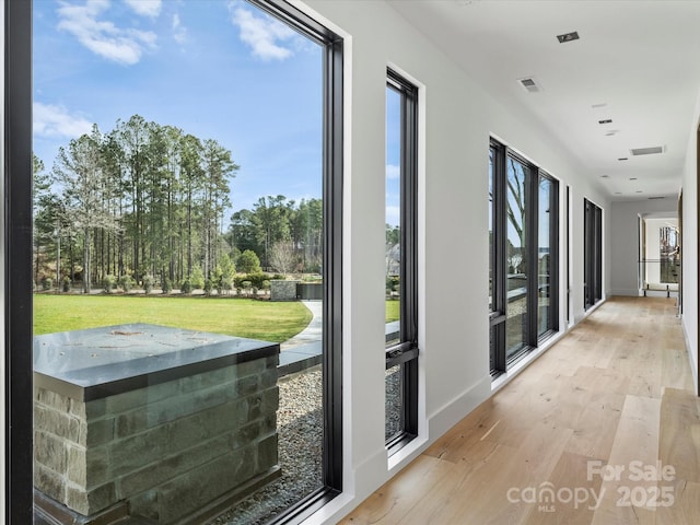 doorway with light wood-type flooring, visible vents, and baseboards