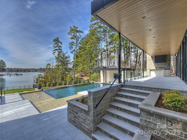 outdoor pool with a patio area, an outdoor kitchen, and a water view