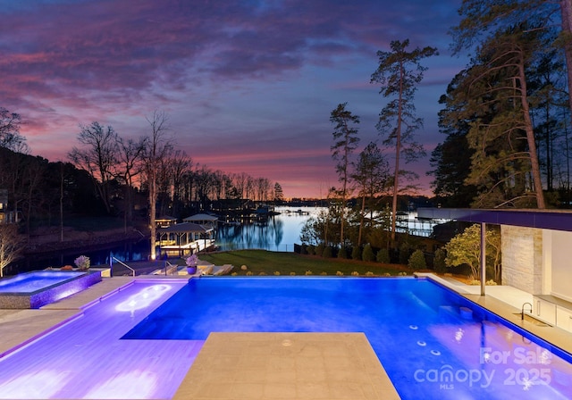 pool featuring an in ground hot tub, a yard, a patio, and a water view